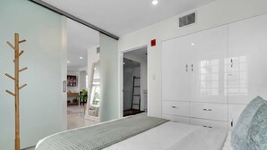 Un dormitorio moderno con cama, armario y perchero.