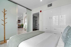 A modern bedroom with a bed, wardrobe, and a coat rack. - South Beach 1BR on Ocean Drive · Steps to the Sand (Miami Beach)