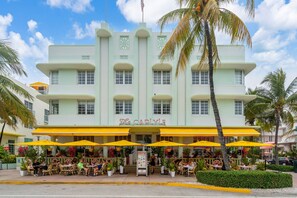 A multi-story building with a cafe named 'The Carlyle' on the ground floor. - South Beach 1BR on Ocean Drive · Steps to the Sand (Miami Beach)