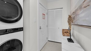 Una sala de lavandería con dos lavadoras, una puerta con señal de salida de incendios y un adorno en la pared.