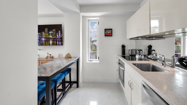 Una cocina moderna con un ventanal grande, horno empotrado y pileta de acero inoxidable.