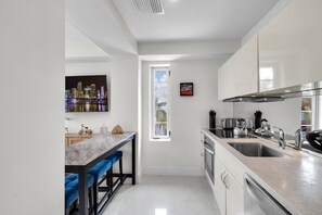 Una cocina moderna con un ventanal grande, horno empotrado y pileta de acero inoxidable.