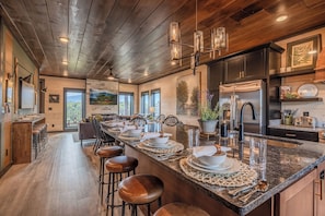 A spacious kitchen with a large island, modern appliances, and a view of the outdoors. - Indoor Pool + Water Park Access | Mtn Views | Sleeps 20 (Sevierville)