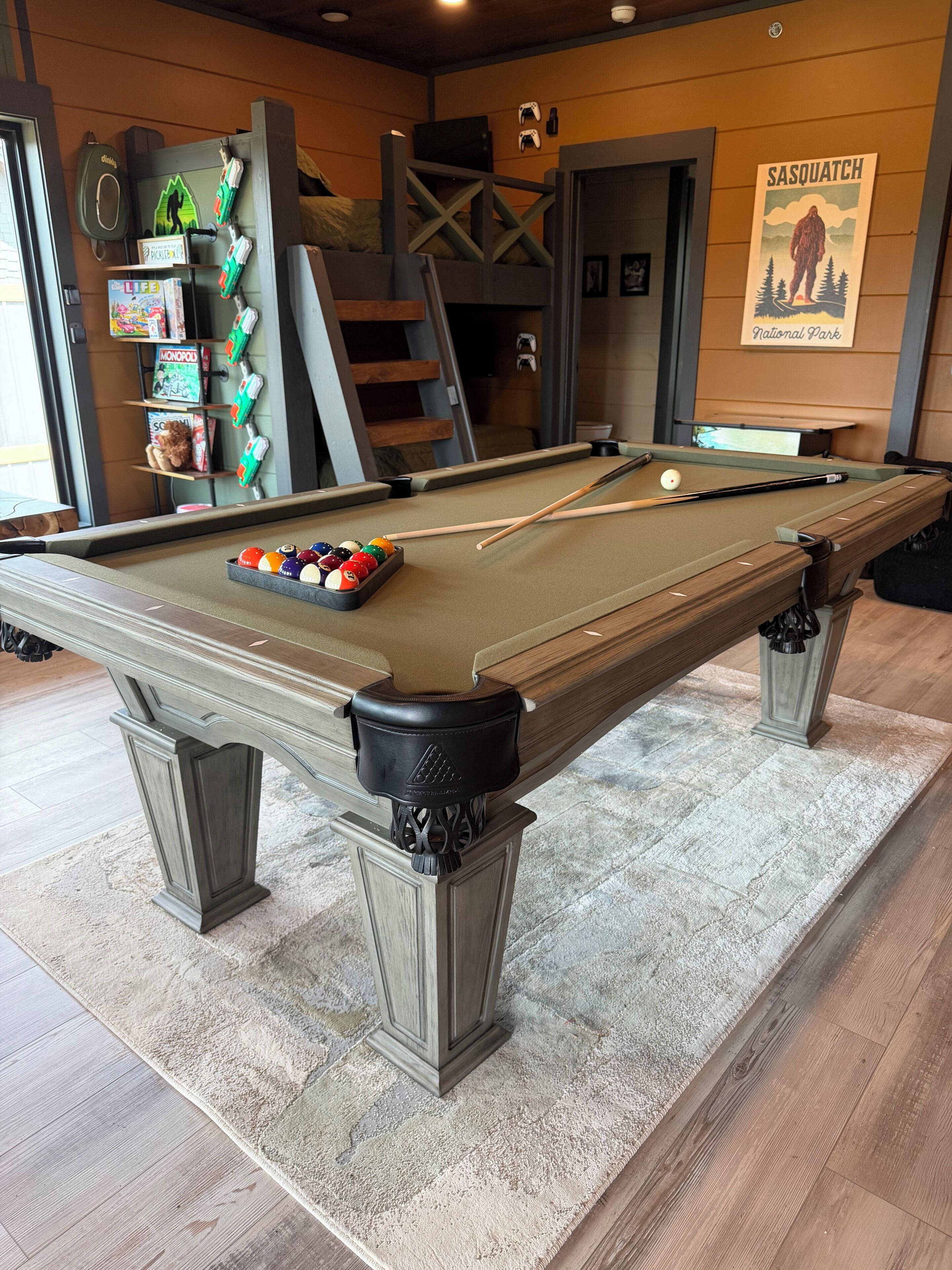 A pool table with a variety of pool balls, a cue stick, and a billiard rack.