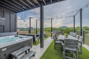 Eine überdachte Terrasse im Freien mit Whirlpool, Sitzgelegenheiten und Lichterketten.