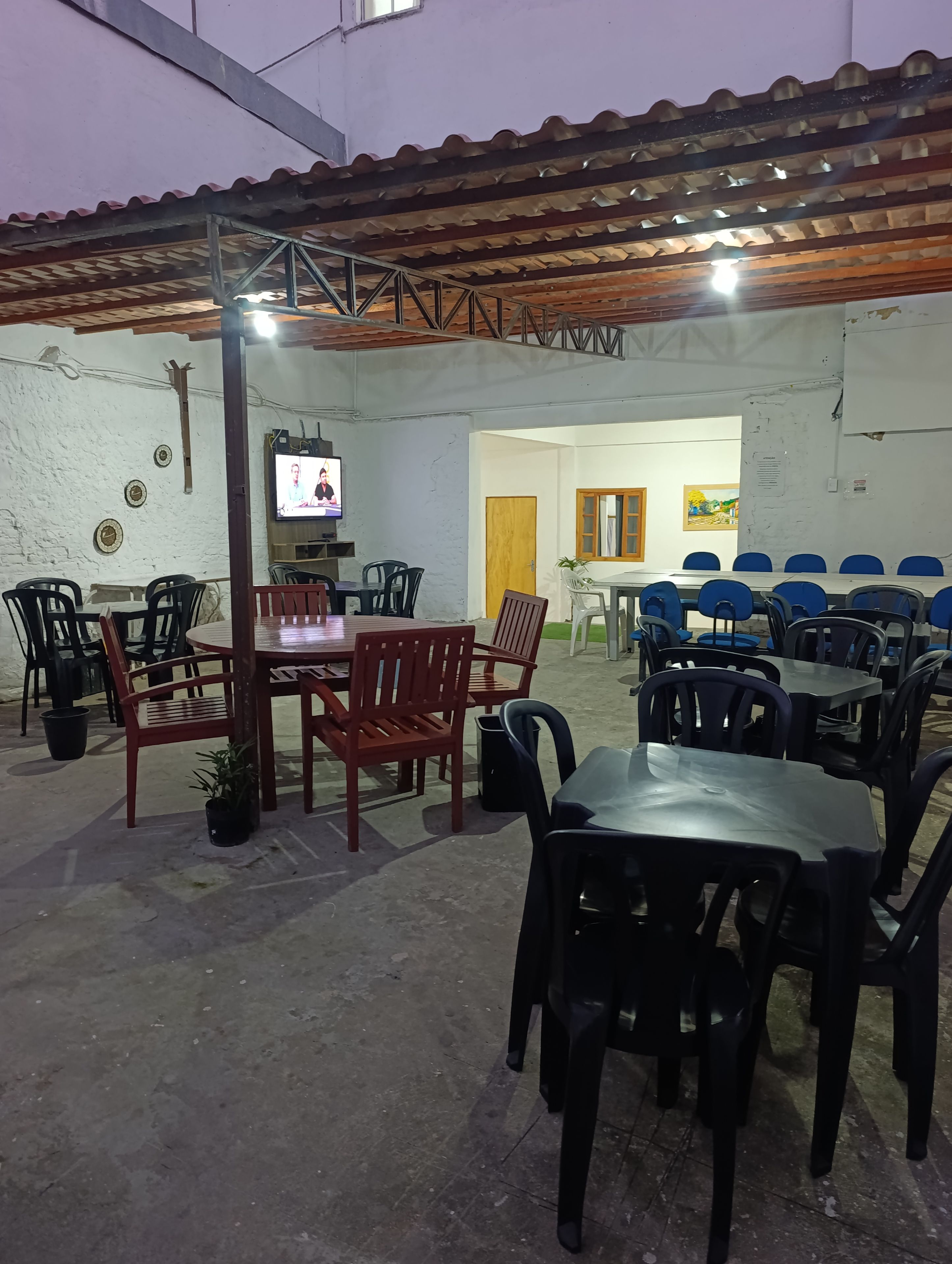An indoor dining area with tables and chairs, a television, and a door leading to another room.