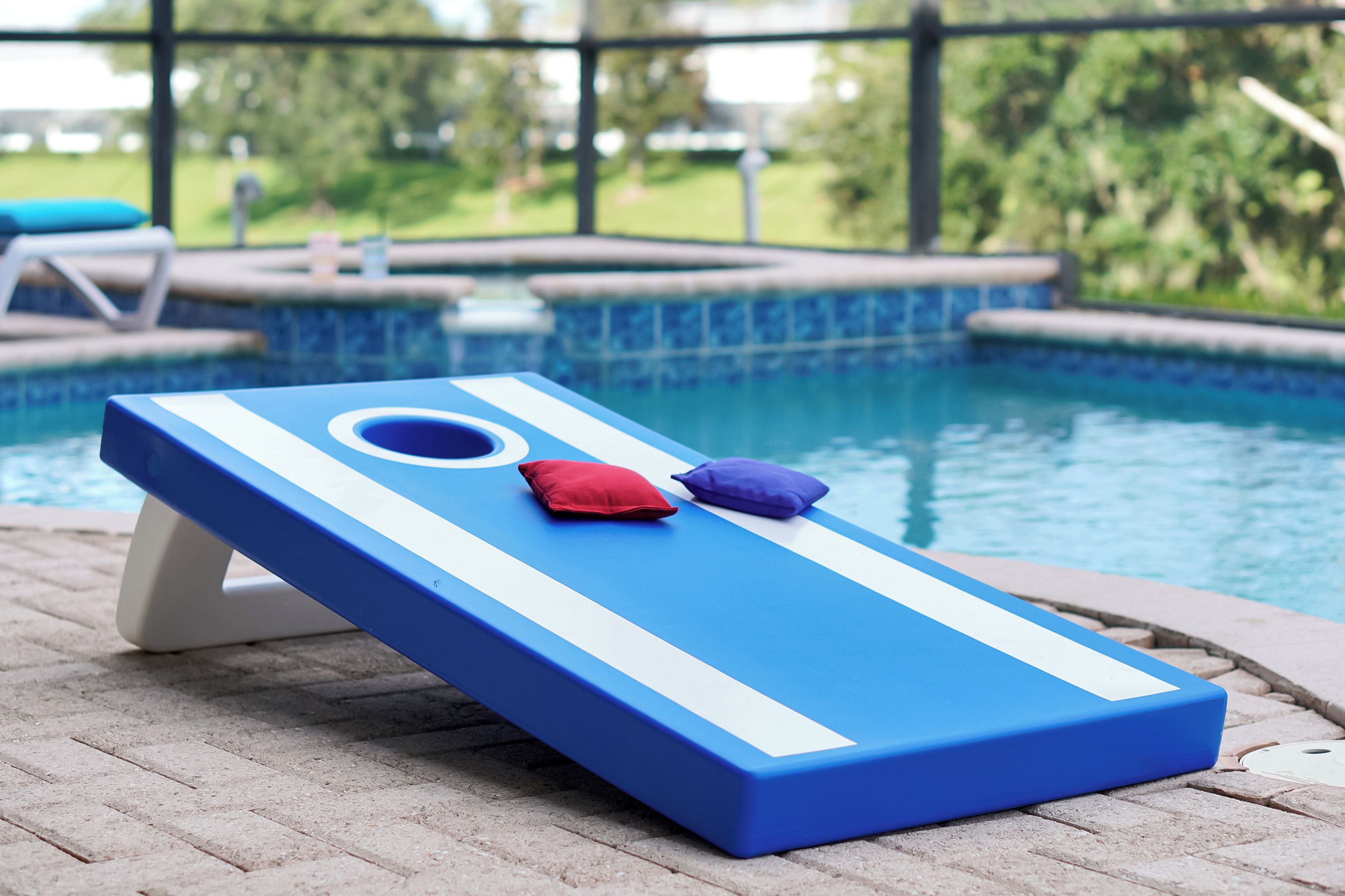 A poolside lounge area with a blue lounge chair and a pool table.