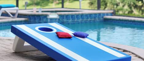 Un área de descanso junto a la piscina con una tumbona azul y una mesa de billar.