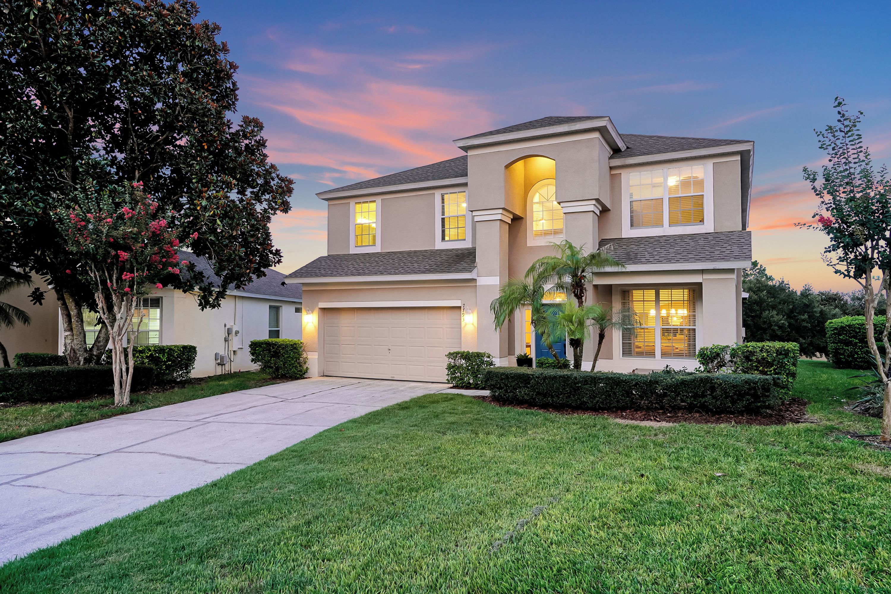 A two-story residential house with a garage, a driveway, and well-maintained landscaping.