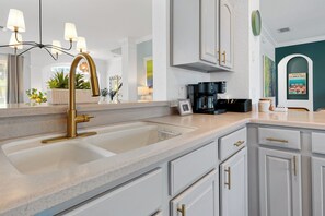 Eine moderne Küche mit goldfarbenem Wasserhahn, weißen Schränken und einer Kaffeemaschine.
