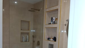 A modern bathroom with a glass-enclosed shower, a toilet, and a vanity with shelves.