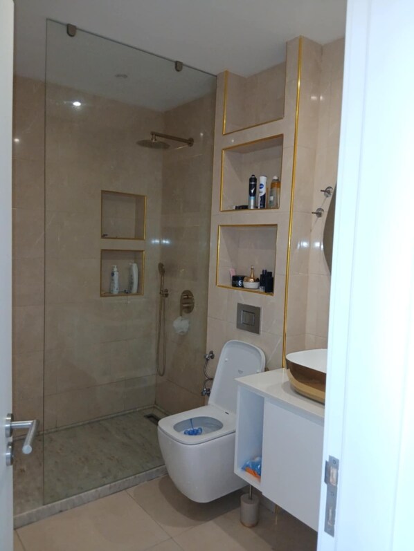 Une salle de bain moderne avec une douche à parois de verre, des toilettes et un meuble-lavabo avec des étagères.