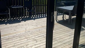 A wooden deck with outdoor furniture, a metal fence, and a building in the background.