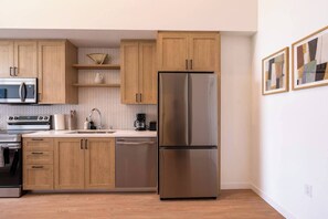 A modern kitchen with wooden cabinets, stainless steel appliances, and a two-door refrigerator.