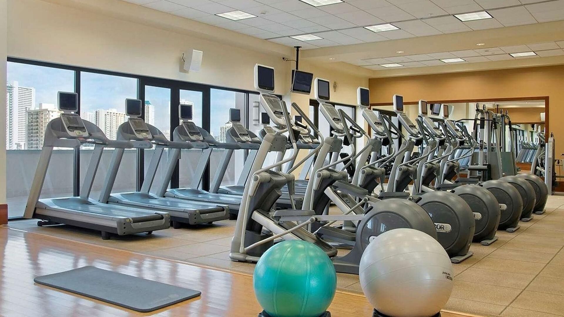Een sportschool met loopbanden, elliptische trainers en fitnessballen.