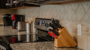 A kitchen with granite countertops, a stainless steel oven, and a knife block with red handles. - Go 13 Windsor AT Westside (Kissimmee)