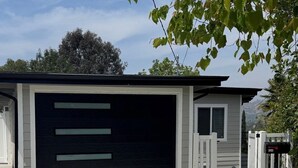 Eine Garage mit einer schwarzen Tür, einem weißen Zaun und einem Briefkasten.