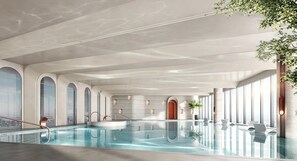 Una piscina interna moderna con barriera in vetro trasparente, finestre ad arco e vista sulla città.