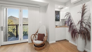 A room with a wicker chair, a potted plant, and a view through a sliding door.