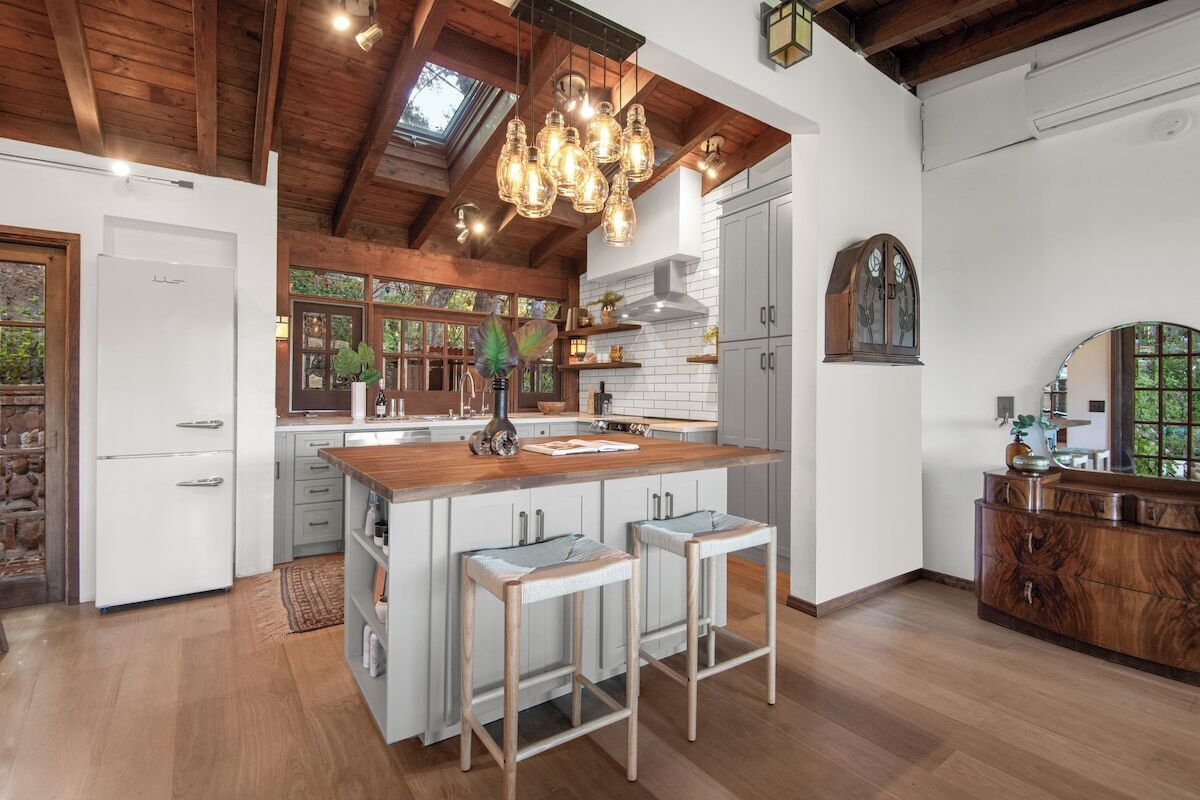 A spacious kitchen with a central island, wooden beams, and pendant lighting.