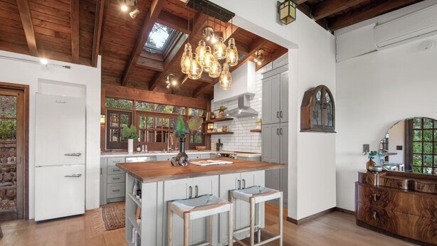 A spacious kitchen with a central island, wooden beams, and pendant lighting.