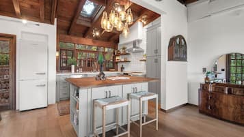 A spacious kitchen with a central island, wooden beams, and pendant lighting.