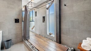 A modern bathroom with a large mirror, a shower, and a wooden bench. - High Tide | Modern Design, Venice Energy (Los Angeles)