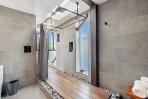 A modern bathroom with a large mirror, a shower, and a wooden bench. - High Tide | Modern Design, Venice Energy (Los Angeles)