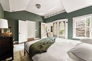 Ein Schlafzimmer mit einem Bett, einem Nachttisch, einer Lampe und einem Fenster mit Blick.