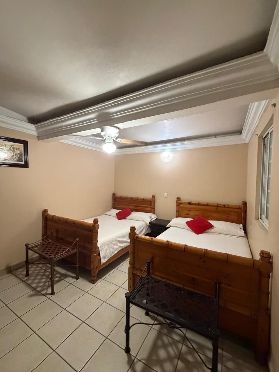 A bedroom with two wooden beds, a ceiling fan, and a window.