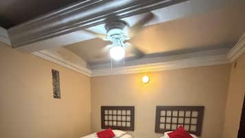 Quarto com duas camas de solteiro, cada uma com cabeceira e uma mesa pequena.