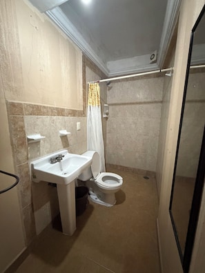 A bathroom with a toilet, sink, and shower area. - Hotel Luz de Luna (Oaxaca)
