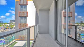 Un balcon offrant une vue dégagée sur le paysage urbain, avec des bâtiments modernes et une rue bordée de palmiers.