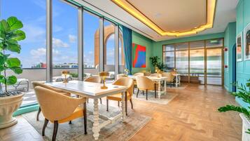 Un vaste espace dédié à la salle à manger, doté de grandes fenêtres, offrant une vue sur le paysage urbain, et présentant un aménagement intérieur moderne.