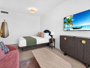 Ein Hotelzimmer mit Bett, Fernseher, Schreibtisch und einer Couch.