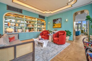 Ein Zimmer mit einer türkisfarbenen Wand, einem Bücherregal, einem Sofa, einem roten Sessel und einem Couchtisch.