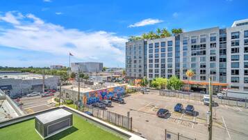 A parking lot with multiple cars, a mural, and modern buildings in the background.