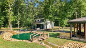 Ein Wohnhaus mit Schwimmbad, einer Holzterrasse und einem überdachten Sitzbereich im Freien.