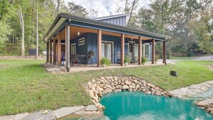Ein Haus mit überdachter Terrasse, Swimmingpool und einem Wasserfall-Element aus Stein.