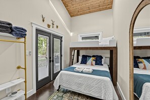 A bedroom with a bunk bed, a door leading to an outdoor area, and a mirror. - Waterfront Blue Spruce w Hot Tub & Fire Pit! (Wildwood)