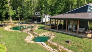 A residential property with a covered patio, a swimming pool, and a bridge. - Waterfront Blue Spruce w Hot Tub & Fire Pit! (Wildwood)