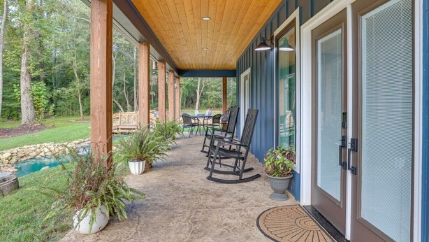 Un patio cubierto con mobiliario exterior, un sendero de piedra y vistas a un paisaje natural.