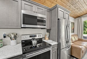 A modern kitchen with stainless steel appliances, a gas stove, and a refrigerator. - Waterfront Blue Spruce w Hot Tub & Fire Pit! (Wildwood)