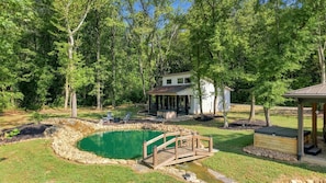 A backyard with a swimming pool, a wooden deck, and a covered patio area. - Whitewood Retreat w Hot Tub, Waterfall Views! (Wildwood)