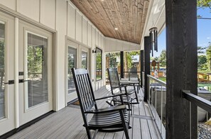Ein überdachter Außenbereich mit Stühlen und einem Tisch, Holzboden und großen Fenstern.