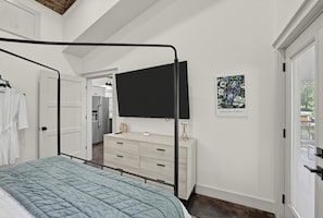 A bedroom with a bed, a dresser, a television, and a door leading to another room. - Whitewood Retreat w Hot Tub, Waterfall Views! (Wildwood)