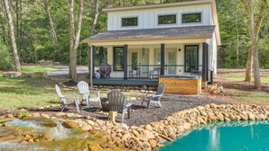 Una casa moderna de dos pisos con un porche cubierto, mobiliario de exterior y una piscina.