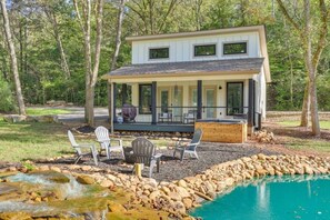 Ein modernes, zweistöckiges Haus mit überdachter Terrasse, Sitzgelegenheiten im Freien und einem Swimmingpool.
