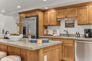 A modern kitchen with wooden cabinets, a stainless steel refrigerator, granite countertops, and a coffee maker. - Park City Retreat | A/C + Hot Tub + Shared Pool (Park City)