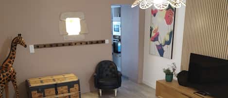 A living room with a sofa, a coffee table, a television, and a giraffe statue.